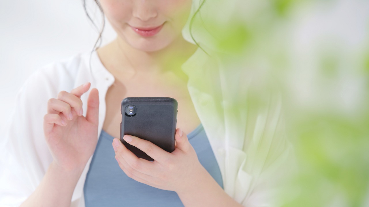 植物の向こうでスマホ操作